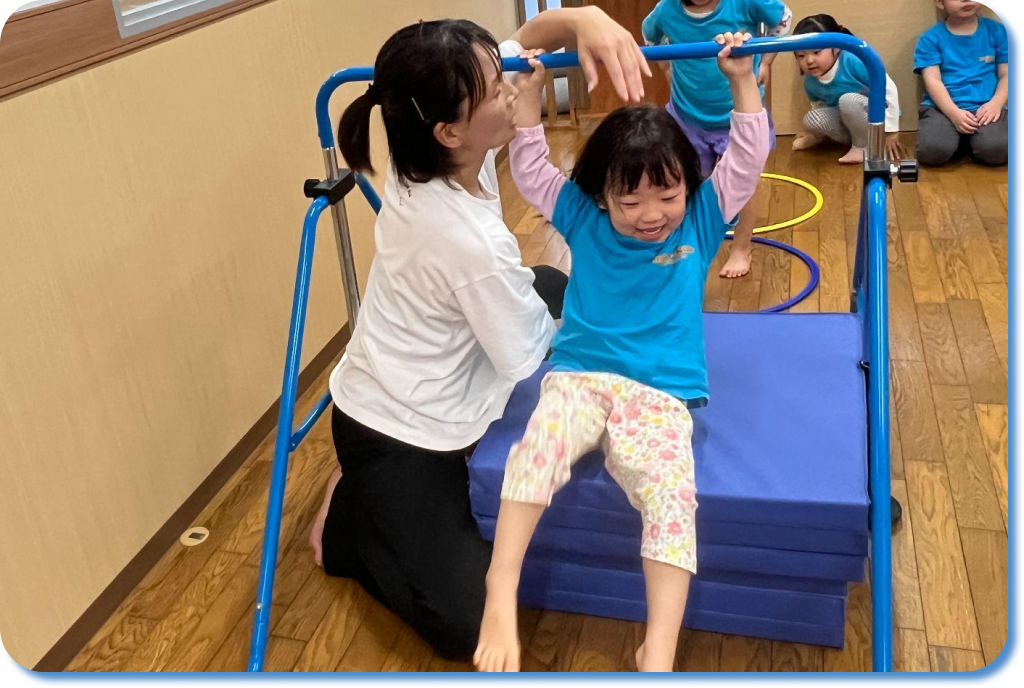 体操のアクティビティで鉄棒をする園児