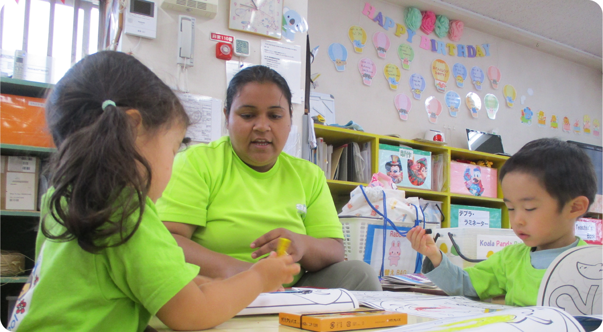 外国人スタッフとお絵かきする園児たち