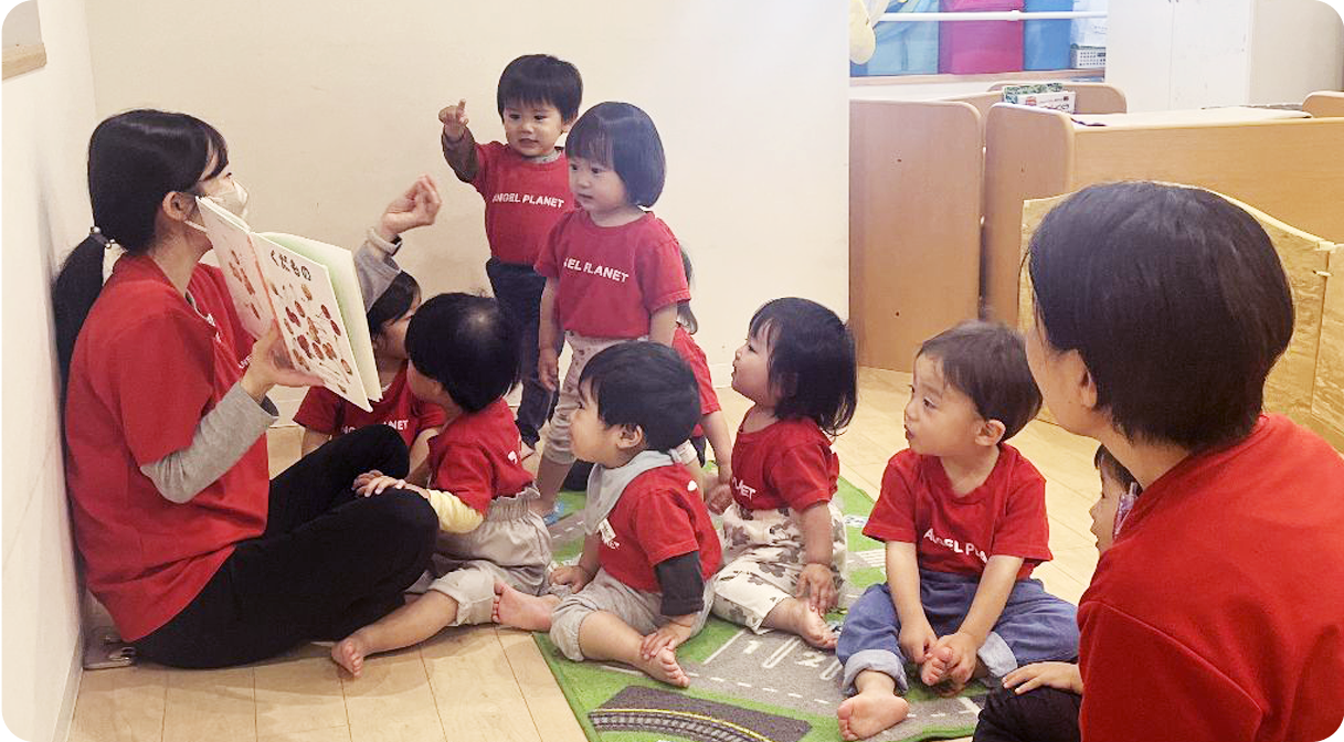 保育士に絵本を読んでもらう園児たち