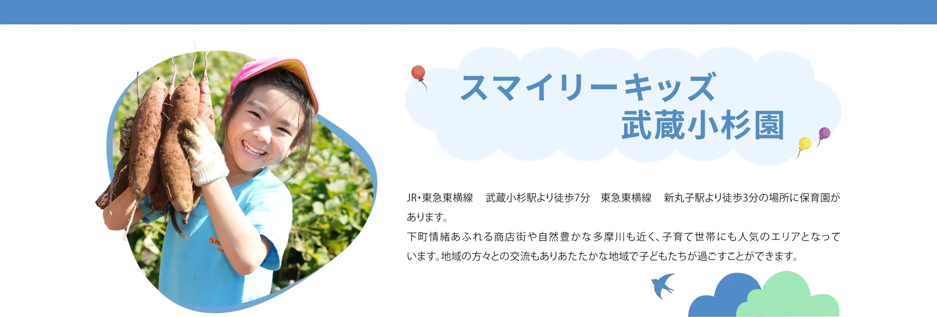 掘ったさつまいもを手に持って笑顔の園児